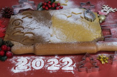 Kırmızı zemin üzerinde ahşap bir tahtada ev yapımı zencefilli kurabiye yapmak için Hamur. Noel ve Yeni Yıl 2022 konsepti. Seçici odak