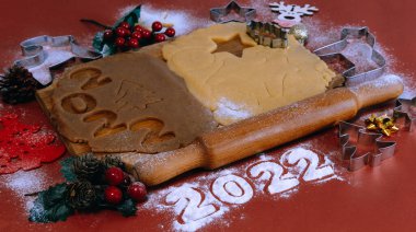 Kırmızı zemin üzerinde ahşap bir tahtada ev yapımı zencefilli kurabiye yapmak için Hamur. Noel ve Yeni Yıl 2022 konsepti. Seçici odak