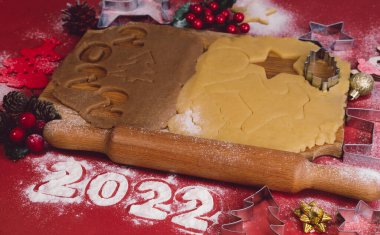 Kırmızı zemin üzerinde ahşap bir tahtada ev yapımı zencefilli kurabiye yapmak için Hamur. Noel ve Yeni Yıl 2022 konsepti. Seçici odak