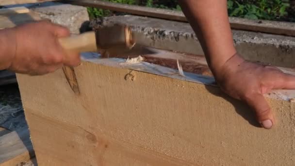 El carpintero trabaja con un hacha sobre madera. — Vídeo de stock