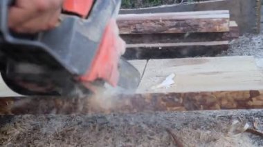 Çevre dostu ve doğal malzemelerden ev inşa etmek için tahta testeresi kullanan bir adam..