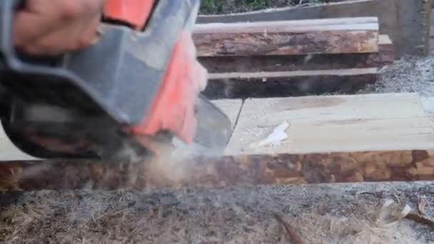 Muž piluje dřevěné desky pro stavbu domu z ekologických a přírodních materiálů. — Stock video