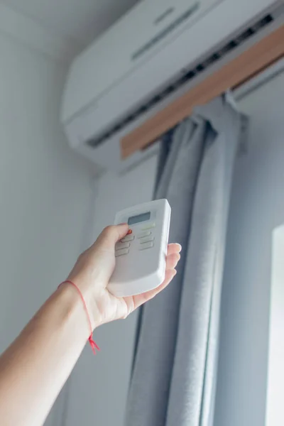 Main masculine tient une télécommande du climatiseur. Il y a un climatiseur sur le mur en arrière-plan. Accueil concept de contrôle climatique. Images De Stock Libres De Droits