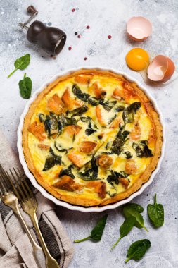 Kırmızı balık ve hafif ahşap zemin üzerine ıspanak ile ev yapımı kiş tart. Vintage tarzı. Üstten Görünüm