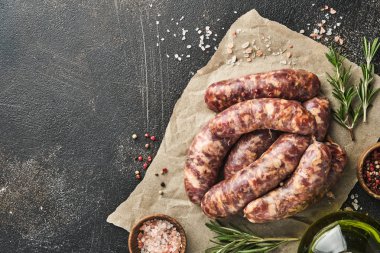 Çiğ sosis ya da sucuk ve koyu taş arka planda pişirmek için malzemeler. Kopyalama alanı olan üst görünüm.