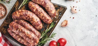 Çiğ sosis ya da baharat ve yemek pişirmek için malzemelerle kesilmiş sosis. Açık gri taş tablo üzerinde kopyalama alanı olan üst görünüm.