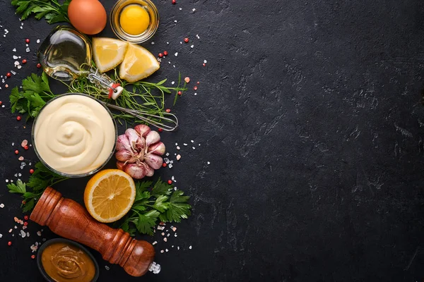 Ev yapımı mayonez sosu ve limon, yumurta, zeytinyağı, baharat ve otlar, siyah arka plan fotokopi alanı. Yemek pişirme geçmişi. Üst görünüm.