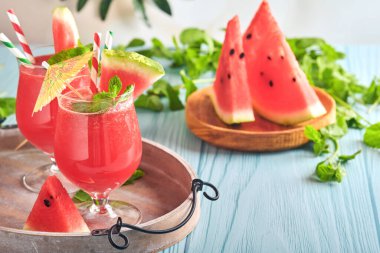 Naneli ve buzlu karpuz kokteyli. Yaz aylarında mavi ahşap masadaki bardaklarla içecekleri tazeliyorum. Sağlıklı yaz yemekleri kavramı.