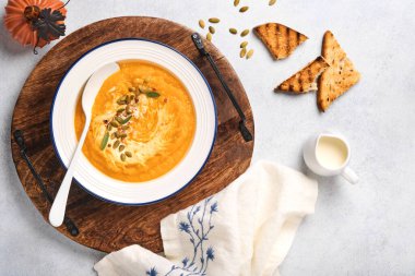 Balkabağı geleneksel çorbası kremalı ipeksi desenli adaçayı ve beyaz tabakta kırmızı biber. Açık gri arkaplan. Uzayı kopyala Model yap. Üst manzara, düz uzanma.