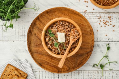 Eski beyaz ahşap arka planda maydanoz yaprağı ve tereyağlı karabuğday lapası. Ev yapımı yemek. Sağlıklı beslenme için glütensiz antik tahıl. Üst Manzara. Boşluğu kopyala.