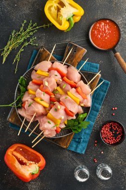 Ahşap tahtada çiğ şiş kebap, baharatlar, otlar ve koyu gri arka planda sebzeler. Gulaş ya da şiş kebap için mangal malzemesi. Üst Manzara. Boş kopyalama alanı.