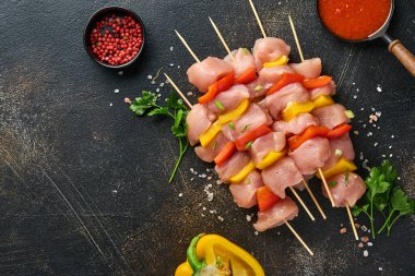 Ahşap tahtada çiğ şiş kebap, baharatlar, otlar ve koyu gri arka planda sebzeler. Gulaş ya da şiş kebap için mangal malzemesi. Üst Manzara. Boş kopyalama alanı.