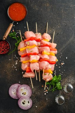 Ahşap tahtada çiğ şiş kebap, baharatlar, otlar ve koyu gri arka planda sebzeler. Gulaş ya da şiş kebap için mangal malzemesi. Üst Manzara. Boş kopyalama alanı.