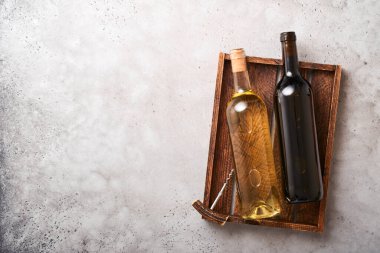 Eski gri beton masa zemininde, üzerinde üzüm ve şarap kadehleri olan iki şarap şişesi. Asma dallı kırmızı şarap. Kırsal arka planda şarap kompozisyonu. Model.