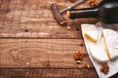 Tirbuşonlu bir şişe şarap. Üzümlü, peynirli Camembert dilimli, eski gri beton masa arkaplanlı ve fotokopi alanı olan. Asma dallı kırmızı şarap. Kırsal arka planda şarap kompozisyonu. Model.