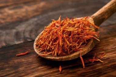 Eski ahşap arka planda kaşık içinde kırmızı safran. Geçmişi ve dokusu. Model.