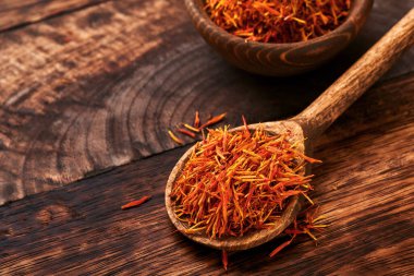 Eski ahşap arka planda kaşık içinde kırmızı safran. Geçmişi ve dokusu. Model.