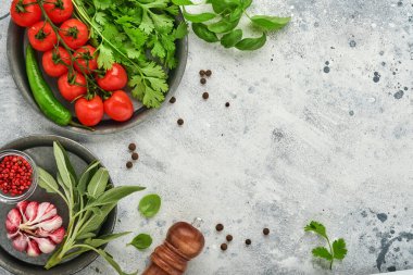 Yemek pişirme geçmişi. Taze safran, sarımsak, kişniş, fesleğen, kiraz domatesleri, biber ve zeytinyağı, baharat ve sebzeler açık gri kayrak masada. Gıda malzemeleri üst görünüm.