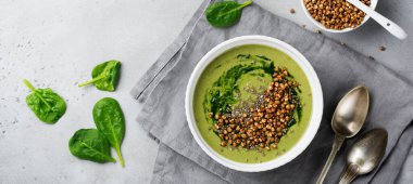 Yararlı smoothies buğday gevreği gri beton tablo arka plan üzerinde seramik kase ıspanak üzerinden. Seçici odak. Üstten Görünüm. Kopya alanı.