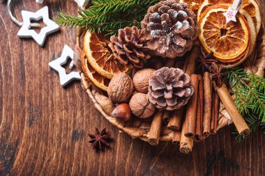 Kuru portakal, yıldız anason, tarçın, çam kozalağı ve ahşap masadaki kırsal tabakta köknar ağacı. Noel havası ve aroma için ev yapımı karışık bir fikir. Ev yapımı doğal süslemeleri olan çevre dostu bir Noel..