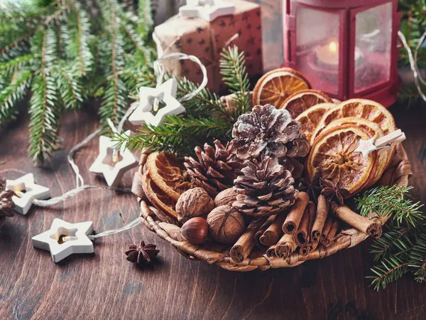 Kuru portakal, yıldız anason, tarçın, çam kozalağı ve ahşap masadaki kırsal tabakta köknar ağacı. Noel havası ve aroma için ev yapımı karışık bir fikir. Ev yapımı doğal süslemeleri olan çevre dostu bir Noel..