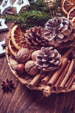 Kuru portakal, yıldız anason, tarçın, çam kozalağı ve ahşap masadaki kırsal tabakta köknar ağacı. Noel havası ve aroma için ev yapımı karışık bir fikir. Ev yapımı doğal süslemeleri olan çevre dostu bir Noel..