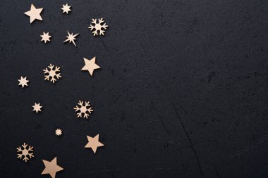 Noel süslemesi. Tahta oyuncaklarla süslenmiş bayram süslemeleri ve siyah arka planda yıldızlar. Sınır tasarımı. Model yap. Üst görünüm.