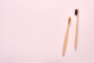 Fotokopi alanı olan pembe arka planda diş ve diş bakımı ürünleri. Çevre dostu bambu diş fırçaları ve pamuk çiçekleri. Düz konum, üst görünüm kompozisyon, model. Sabah konsepti.