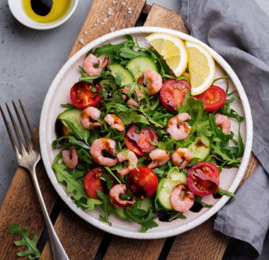 Roka, salatalık, domates ve karides salatası soya sosu bir seramik tabak. Seçici odak. Üstten görünüm.