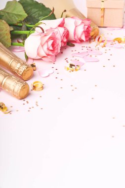 Pembe güller, şampanya, hediye, altın kurdeleler ve pembe arka planda kırmızı kalpler. Tebrik etmek için en üstteki dairede yer var. Sevgililer Günü arkaplanı ve tebrik kartı.