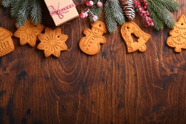 Noel ağacı dalları, Noel baloları, Noel zencefilli çörekleri, hediye kutusu, tahta kar taneleri ve eski ahşap arka planda eski Noel kutlamaları için yıldızlar. Üst görünüm, boşluğu kopyala. Noel tebrik kartı..