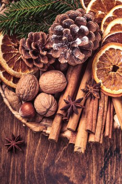 Kuru portakal, yıldız anason, tarçın, çam kozalağı ve ahşap masadaki kırsal tabakta köknar ağacı. Noel havası ve aroma için ev yapımı karışık bir fikir. Ev yapımı doğal süslemeleri olan çevre dostu bir Noel..