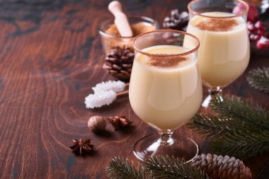 Eggnog Noeli. Lezzetli kış kokteyl sütü, rom ve tarçın iki bardakta servis ediliyor. Şekerli kurabiyeler, beyaz ahşap masa üzerinde köknar dalı. Kapatın. Model.