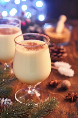 Eggnog Noeli. Lezzetli kış kokteyl sütü, rom ve tarçın iki bardakta servis ediliyor. Şekerli kurabiyeler, beyaz ahşap masa üzerinde köknar dalı. Kapatın. Model.