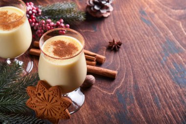 Eggnog Noeli. Lezzetli kış kokteyl sütü, rom ve tarçın iki bardakta servis ediliyor. Şekerli kurabiyeler, beyaz ahşap masa üzerinde köknar dalı. Kapatın. Model.