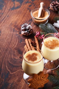 Eggnog Noeli. Lezzetli kış kokteyl sütü, rom ve tarçın iki bardakta servis ediliyor. Şekerli kurabiyeler, beyaz ahşap masa üzerinde köknar dalı. Kapatın. Model.