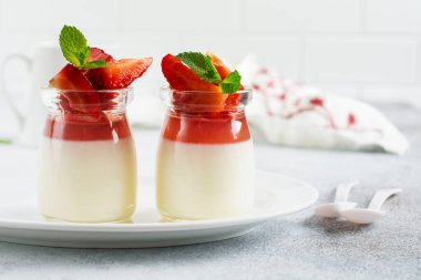 Meyveli tatlı, vanilyalı panna kota ve gri beton masa arkasında taze çilek. Seçici odak