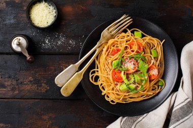 Pesto soslu spagetti makarna, avokado ve kırsal beyaz tabakta domates. Çiğ vejetaryen gıda konsepti. Üst görünüm.