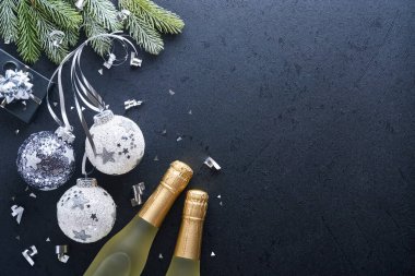 Noel ya da yeni yıl konsepti siyah ve gümüş takılar top, hediye kutusu ve siyah arka planda gümüş metalik kurdeleyle süslenmiş şampanya. Mutlu yıllar 2022. Model.