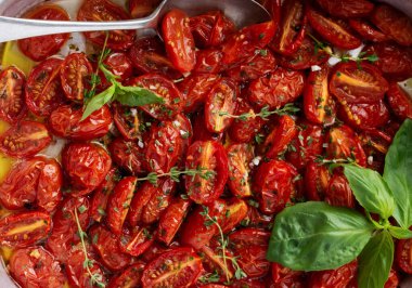 Sarımsaklı, kekik ve fesleğenli fırında kiraz domatesli beton rengi arka planda eski bir tavada. Üst görünüm.