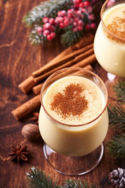 Eggnog Noeli. Lezzetli kış kokteyl sütü, rom ve tarçın iki bardakta servis ediliyor. Şekerli kurabiyeler, beyaz ahşap masa üzerinde köknar dalı. Kapatın. Model.