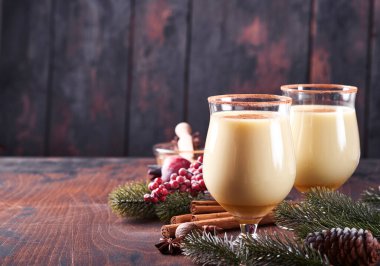 Eggnog Noeli. Lezzetli kış kokteyl sütü, rom ve tarçın iki bardakta servis ediliyor. Şekerli kurabiyeler, beyaz ahşap masa üzerinde köknar dalı. Kapatın. Model.