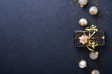Tatil hediyesi kutusu ya da kurdele, altın konfeti ve siyah arka planda altın takılar. Sihirli Noel tebrik kartı. Noel süslemesi. Sınır tasarımı. Model yap. Üst görünüm.