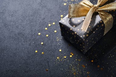 Tatil hediyesi kutusu ya da kurdele, altın konfeti ve siyah arka planda altın takılar. Sihirli Noel tebrik kartı. Noel süslemesi. Sınır tasarımı. Model yap. Üst görünüm.