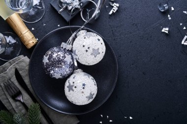 Noel ağacı dallarıyla siyah renkli Noel masası, Noel gümüş topları ve şampanya, yılbaşı kutlamaları için siyah arka planda gözlük. Mutlu Noeller ve mutlu yıllar konsepti