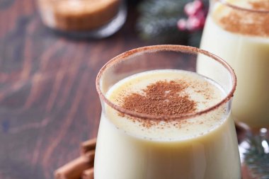 Eggnog Noeli. Lezzetli kış kokteyl sütü, rom ve tarçın iki bardakta servis ediliyor. Şekerli kurabiyeler, beyaz ahşap masa üzerinde köknar dalı. Kapatın. Model.