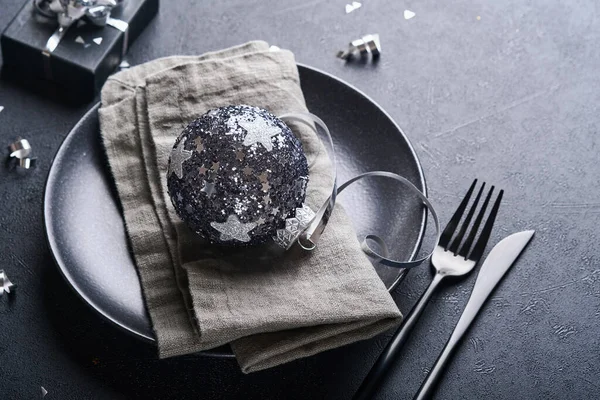 Noel ağacı dallarıyla siyah renkli Noel masası, Noel gümüş topları ve şampanya, yılbaşı kutlamaları için siyah arka planda gözlük. Mutlu Noeller ve mutlu yıllar konsepti