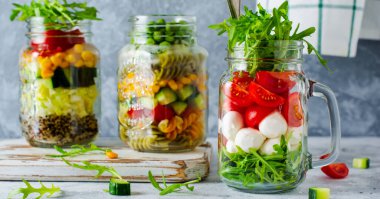 İtalyan roka salatası, mozzarella ve masada öğle yemeği için kavanozda servis edilen vişneli domates. Seçici odak.