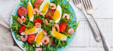 Roka, salatalık, domates, yumurta ve karides salatası soya sosu seramik plaka üzerinde. Seçici odak. Üstten görünüm.