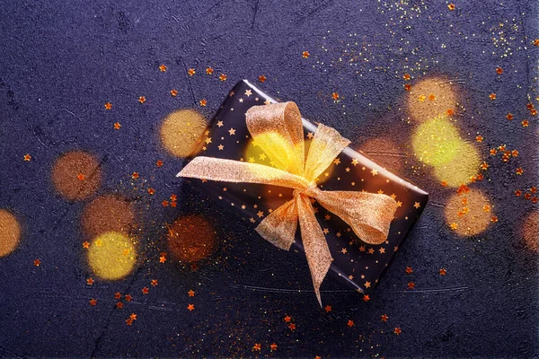 Holiday Gift Box Present Ribbon Golden Confetti Gold Baubles Black — Stock Photo, Image